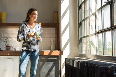 Young woman entrepreneur standing in company kitchen, drinking coffee - SPCF00226