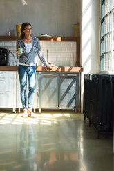 Junge Unternehmerin steht in der Firmenküche und trinkt Kaffee - SPCF00230