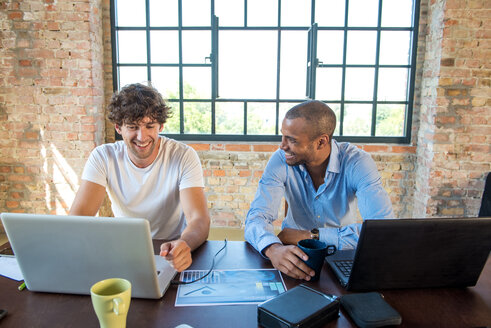 Zwei junge Geschäftsleute arbeiten zusammen in einem Co-Working Space und benutzen Laptops - SPCF00243