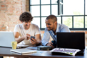 Zwei junge Geschäftsleute arbeiten zusammen in einem Co-Working Space und benutzen Laptops - SPCF00244