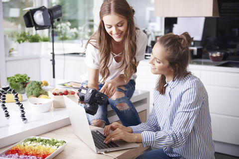 Two food bloggers choosing photos on digital camera stock photo