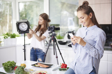 Frau benutzt Smartphone vor dem Kochen - ABIF00036