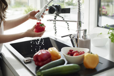 Frau wäscht Gemüse an der Küchenspüle - ABIF00048