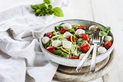 Zoodles Caprese, spiralisierte Zucchini, Glasnudeln, Pesto, Pflaumentomaten, Mozarellakugeln, lizenzfreies Stockfoto