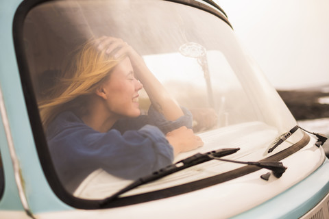 Spanien, Teneriffa, lachende junge Frau im Lieferwagen hinter der Windschutzscheibe sitzend, lizenzfreies Stockfoto