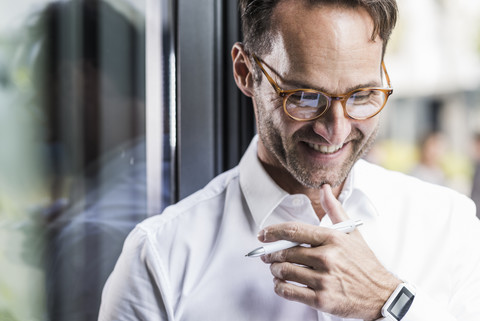 Porträt eines lachenden Geschäftsmannes mit Brille und Smartwatch, lizenzfreies Stockfoto