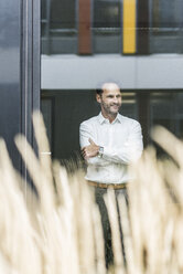 Portrait of smiling businessman looking out of window - UUF12075