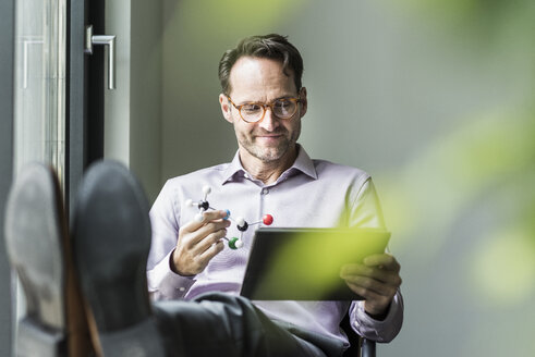 Portrait of smiling man with atomic model and tablet - UUF12086