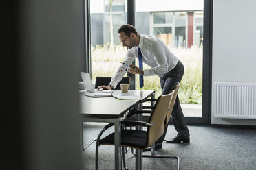 Geschäftsmann mit Atommodell und Laptop in seinem Büro - UUF12090