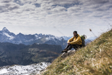 Germany, Bavaria, Oberstdorf, smiling hiker sitting in alpine scenery - UUF12138