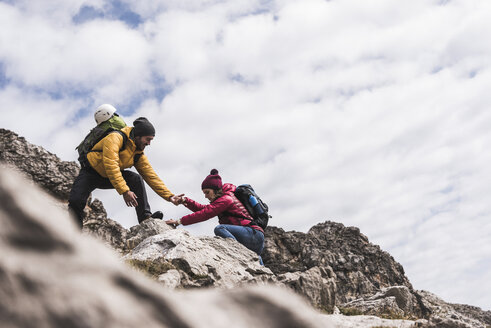 Germany, Bavaria, Oberstdorf, man helping woman climbing up rock - UUF12144