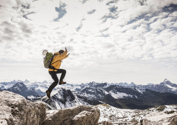 Germany, Bavaria, Oberstdorf, man jumping on rock in alpine scenery - UUF12149