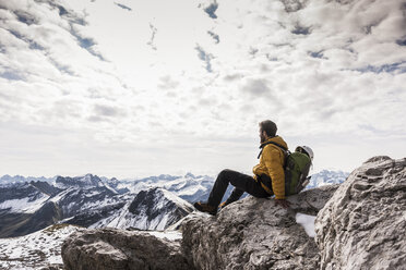 Germany, Bavaria, Oberstdorf, man sitting on rock in alpine scenery - UUF12150