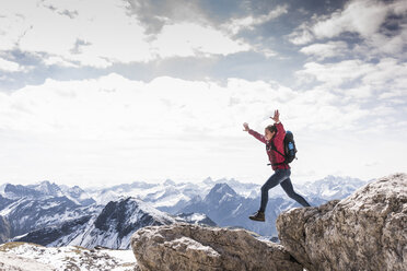 Germany, Bavaria, Oberstdorf, woman jumping on rock in alpine scenery - UUF12151