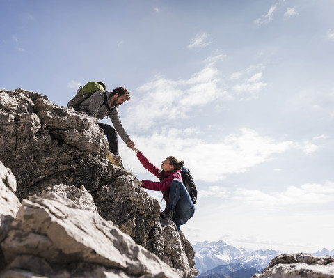 Deutschland, Bayern, Oberstdorf, Mann hilft Frau beim Klettern am Fels, lizenzfreies Stockfoto