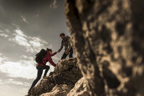 Deutschland, Bayern, Oberstdorf, Mann hilft Frau beim Klettern am Fels, lizenzfreies Stockfoto