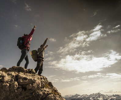 Germany, Bavaria, Oberstdorf, two hikers cheering on rock in alpine scenery - UUF12157