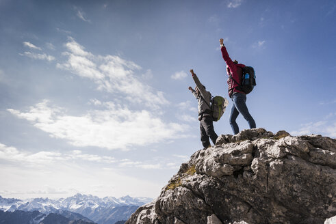 Germany, Bavaria, Oberstdorf, two hikers cheering on rock in alpine scenery - UUF12158