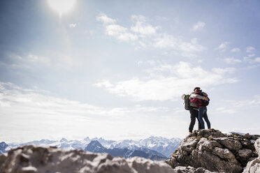 Deutschland, Bayern, Oberstdorf, Paar umarmt auf Felsen in alpiner Landschaft - UUF12160