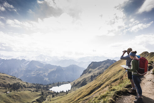 Germany, Bavaria, Oberstdorf, two hikers with map and binoculars in alpine scenery - UUF12176