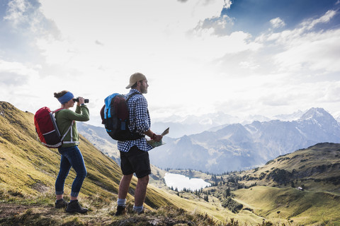 Deutschland, Bayern, Oberstdorf, zwei Wanderer mit Karte und Fernglas in alpiner Kulisse, lizenzfreies Stockfoto