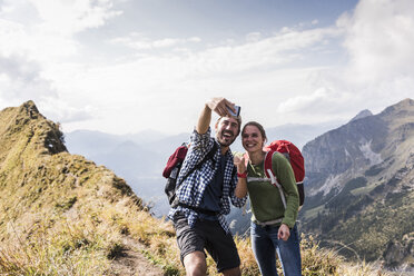 Germany, Bavaria, Oberstdorf, happy couple taking a selfie on mountain ridge - UUF12185