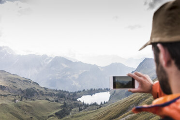 Germany, Bavaria, Oberstdorf, hiker taking picture in alpine scenery - UUF12198