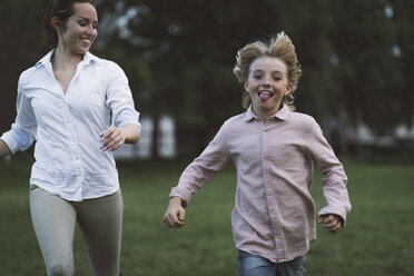 Boy and young woman running on a paddock - KMKF00042