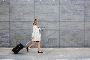 Businesswoman with suitcase wearing trench coat - MGIF00190