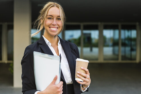 Porträt einer glücklichen Geschäftsfrau mit Dokumenten und Kaffee zum Mitnehmen - MGIF00197