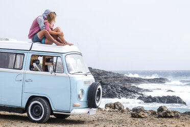 Spain, Tenerife, young couple in love relaxing on car roof of van - SIPF01830