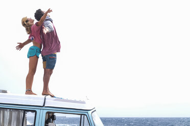 Spanien, Teneriffa, junges Paar steht auf dem Autodach und genießt die Freiheit - SIPF01831