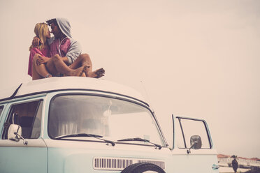 Spain, Tenerife, young couple in love sitting on car roof of van - SIPF01832