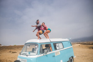 Spanien, Teneriffa, lachendes junges Paar, das auf dem Autodach steht und die Freiheit genießt - SIPF01833
