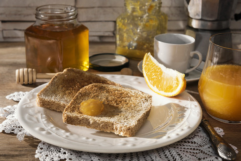 Breakfast table with toast, orange marmalade, honey, orange juice and espresso stock photo