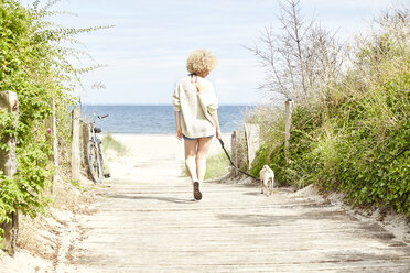 Back view of young woman going walkies with her dog - TSFF00141