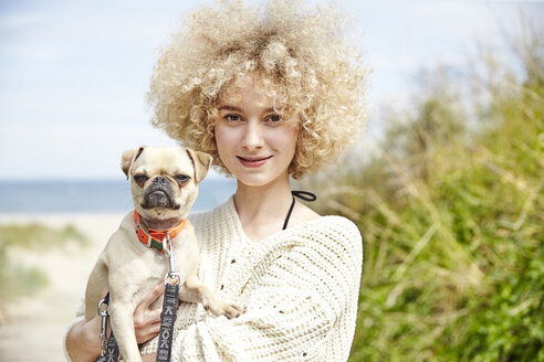 Portrait of smiling young woman holding dog on her arms - TSFF00144