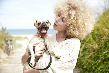 Portrait of young woman holding dog on her arms - TSFF00145