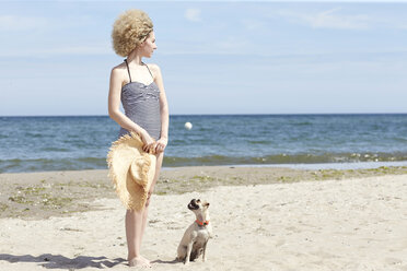 Junge Frau im Badeanzug mit Strohhut und Hund am Strand - TSFF00159