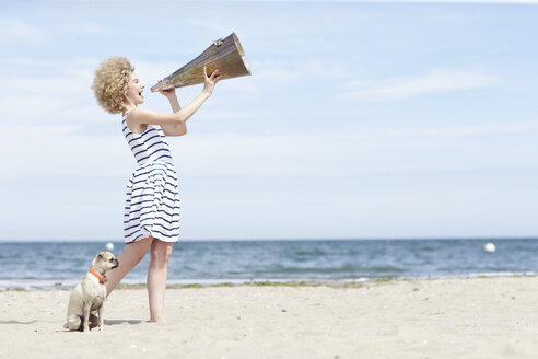 Junge Frau mit Megaphon und Hund am Strand - TSFF00167