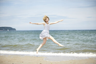 Happy young woman jumping in the air in front of the sea - TSFF00168