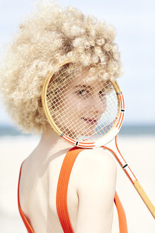 Porträt einer jungen Frau, die durch das Fadenkreuz eines Tennisschlägers am Strand schaut - TSFF00186