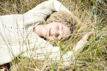 Porträt einer lächelnden jungen Frau mit geschlossenen Augen, die sich in den Stranddünen entspannt - TSFF00190