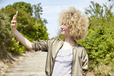 Young blond woman taking selfie with smartphone - TSFF00193