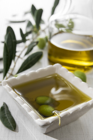 Fresh olive oil in bowl with green olives stock photo