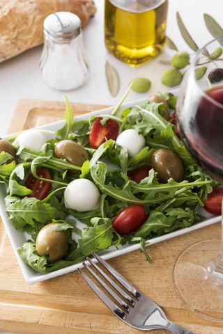 Rucolasalat mit Oliven, Tomaten und Mozzarella, Olivenöl, Rotwein, lizenzfreies Stockfoto
