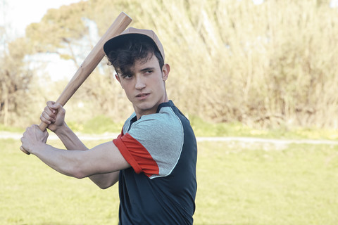 Porträt eines jungen Mannes mit Baseballschläger im Park, lizenzfreies Stockfoto