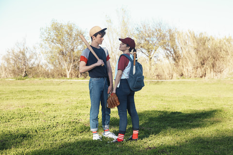 Junges Paar mit Baseball-Ausrüstung im Park, lizenzfreies Stockfoto