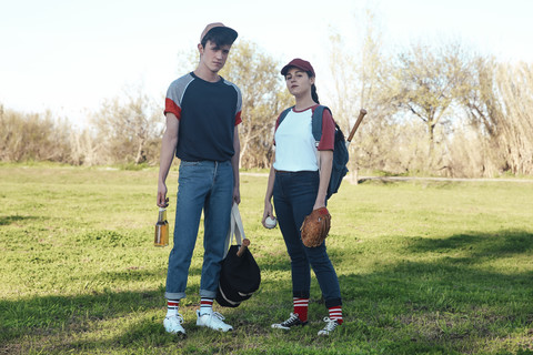 Portrait of young couple with baseball equipment in park stock photo