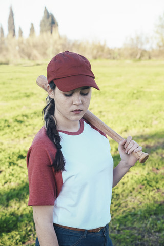 Porträt einer jungen Frau mit Baseballschläger im Park, lizenzfreies Stockfoto